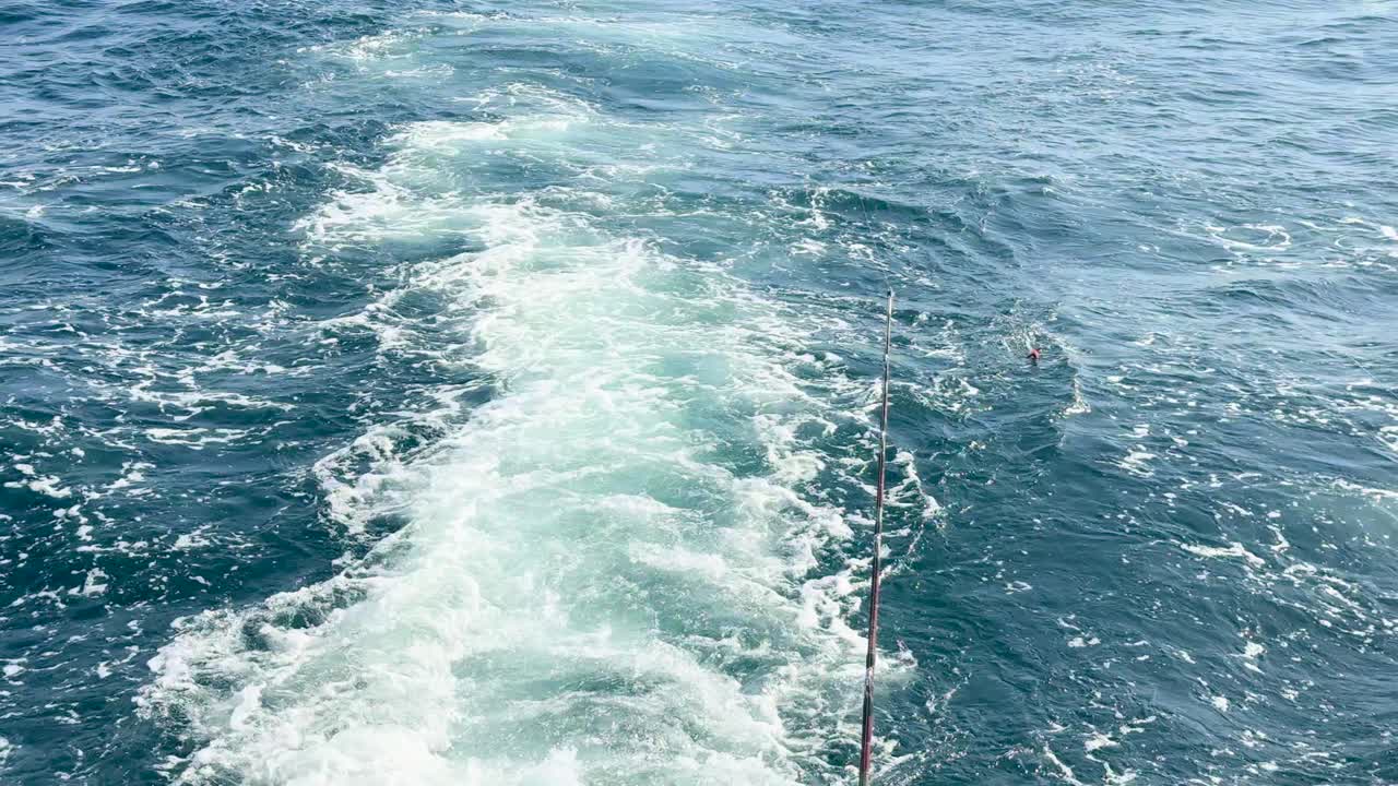 A boat creates a foamy wake in the blue ocean near Ko Racha Yai, under clear skies