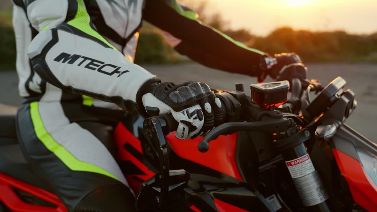 Motorcyclist gripping handlebars of a sport bike during a sunset ride