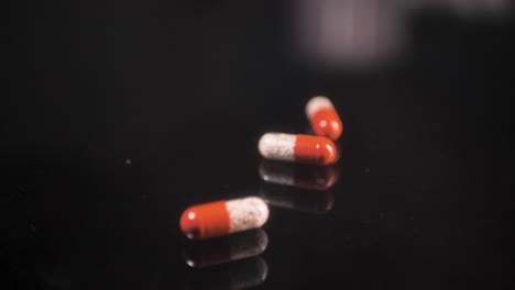 pills falling down on a black glass surface, mirror surface with a reflection on black background