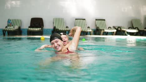 happy smiling little kid is swimming together with his mother in the swimming pool. young mother is spinning and whirling him
