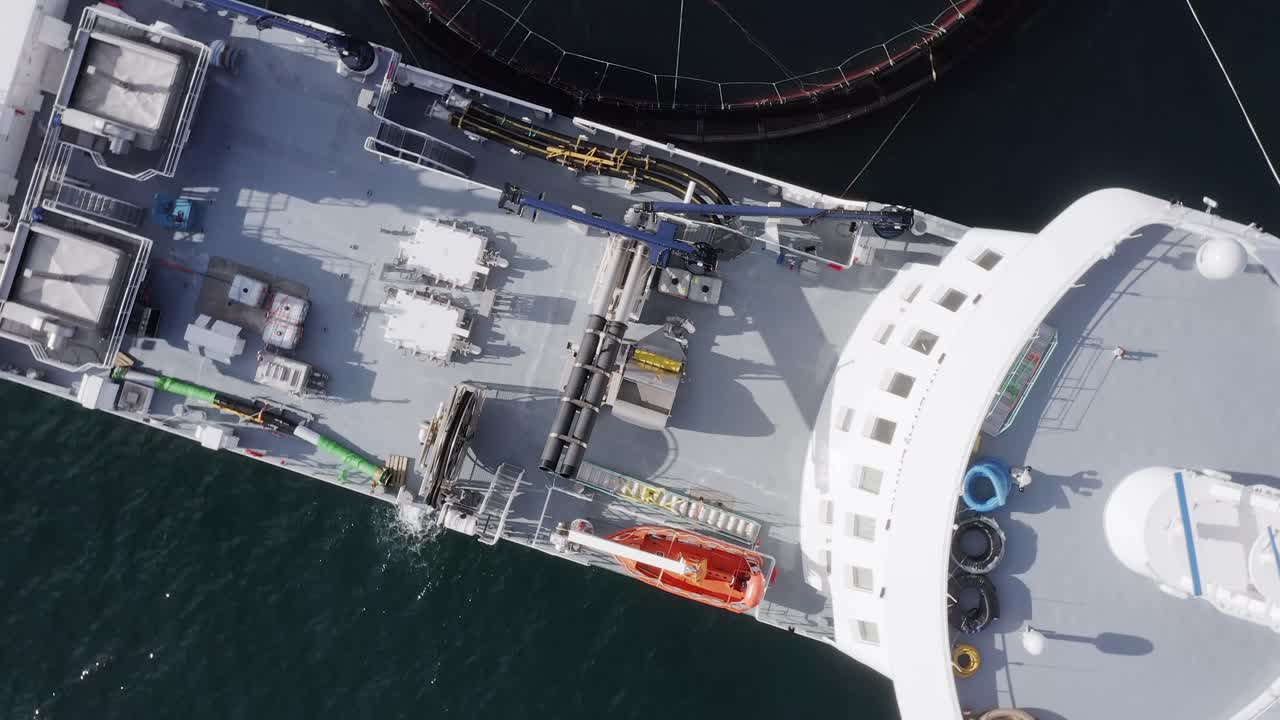 Bird's eye view drone shot of the deck on a docked fish farming vessel
