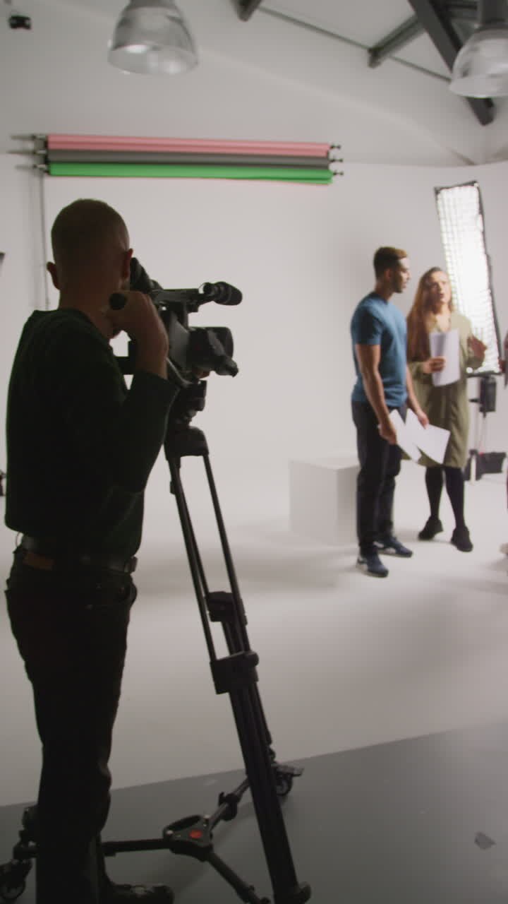 Vertical Video Of Film Camera Operator Shooting Director Talking With Male And Female Actors Holding Scripts Rehearsing For Shooting Movie Or Video In Studio 2