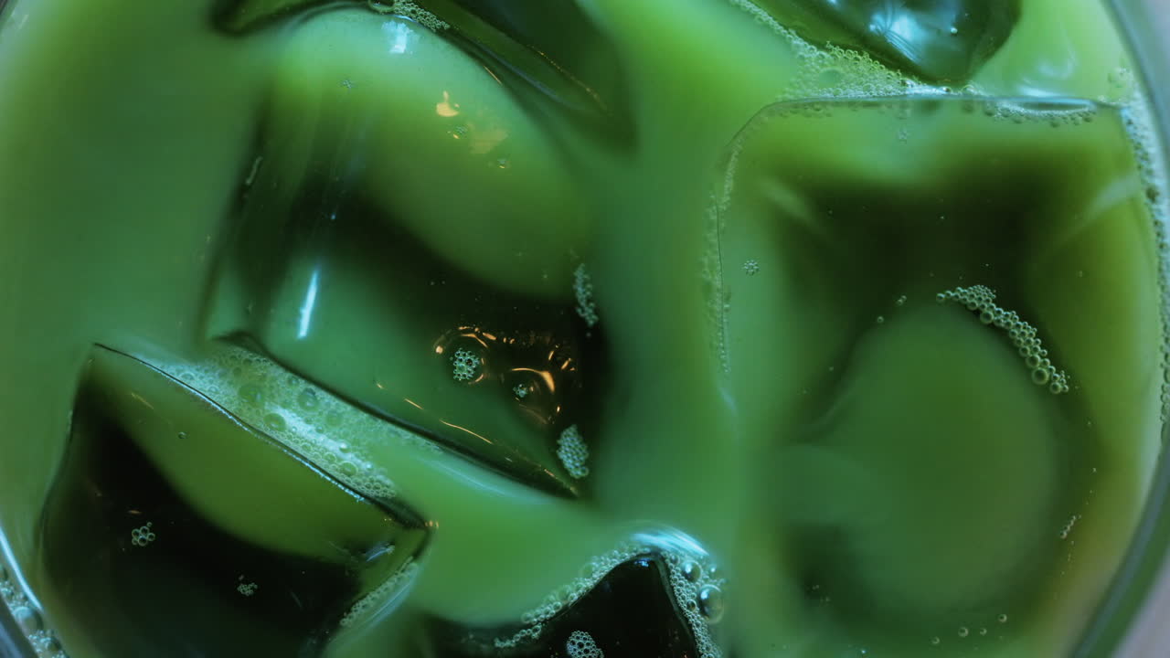 Close up of a glass of an iced matcha on a table at a cafe