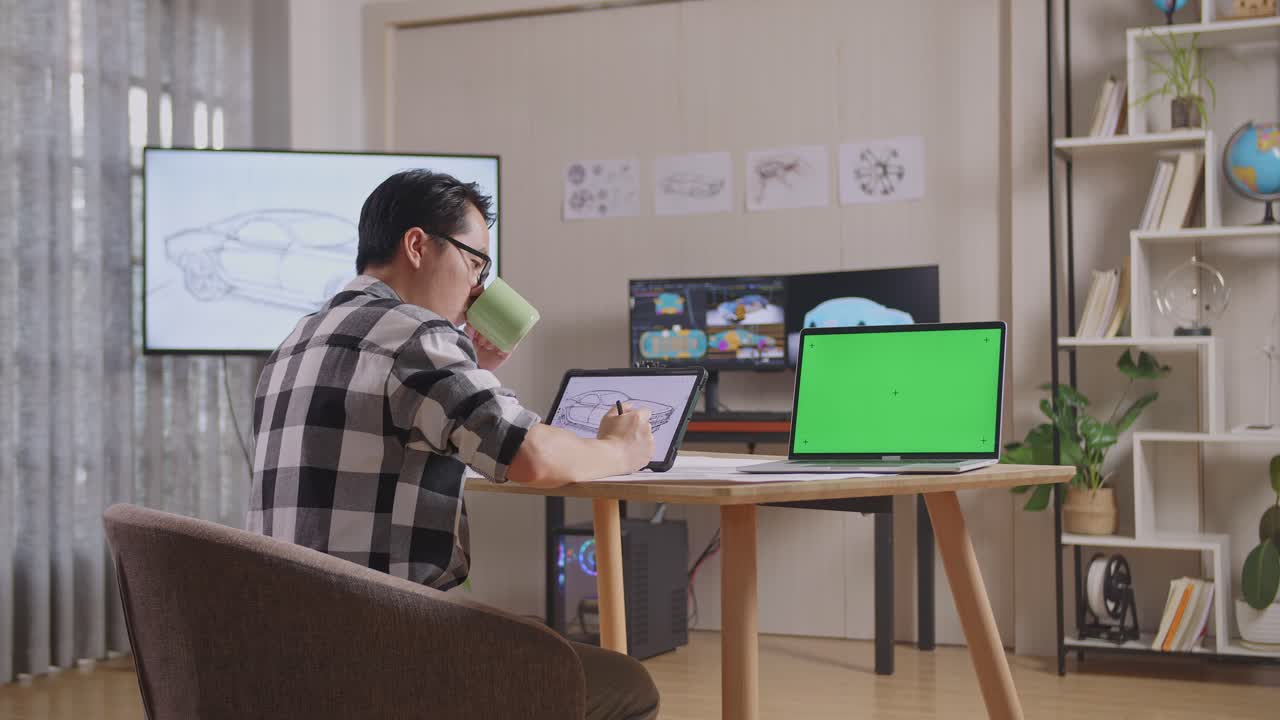 아시아 남성이 커피를 마시며 테이블릿에 자동차 컨셉을 그리는 측면 뷰, tv와 컴퓨터를 가진 스튜디오에서 녹색 스크린 노트북 에 3d 전기 자동차 모델을 표시합니다.