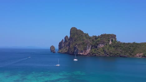 un catamarán está navegando en aguas turquesas cerca de una isla tailandesa tropical en un día soleado
