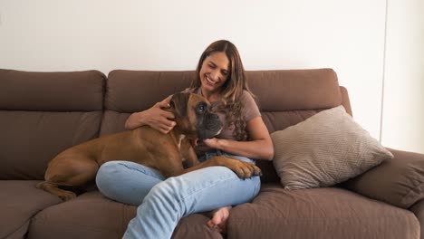 happy woman with cute boxer dog on sofa in apartment