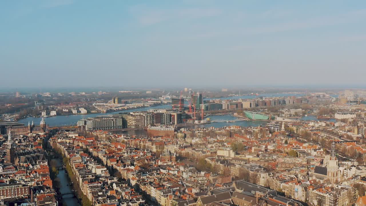 The Beautiful City Of Amsterdam At Daytime - Canals, Historical Buildings, And Central Station In Netherlands, Europe - aerial drone shot