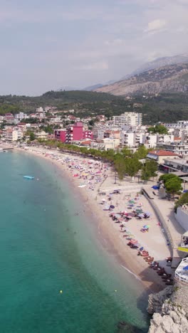 colorful beach in himarë, albania with people relaxing, seen from a vertical drone view