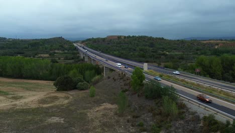 cars drive on a highway through scenic greenery near valencia, spain under an overcast sky