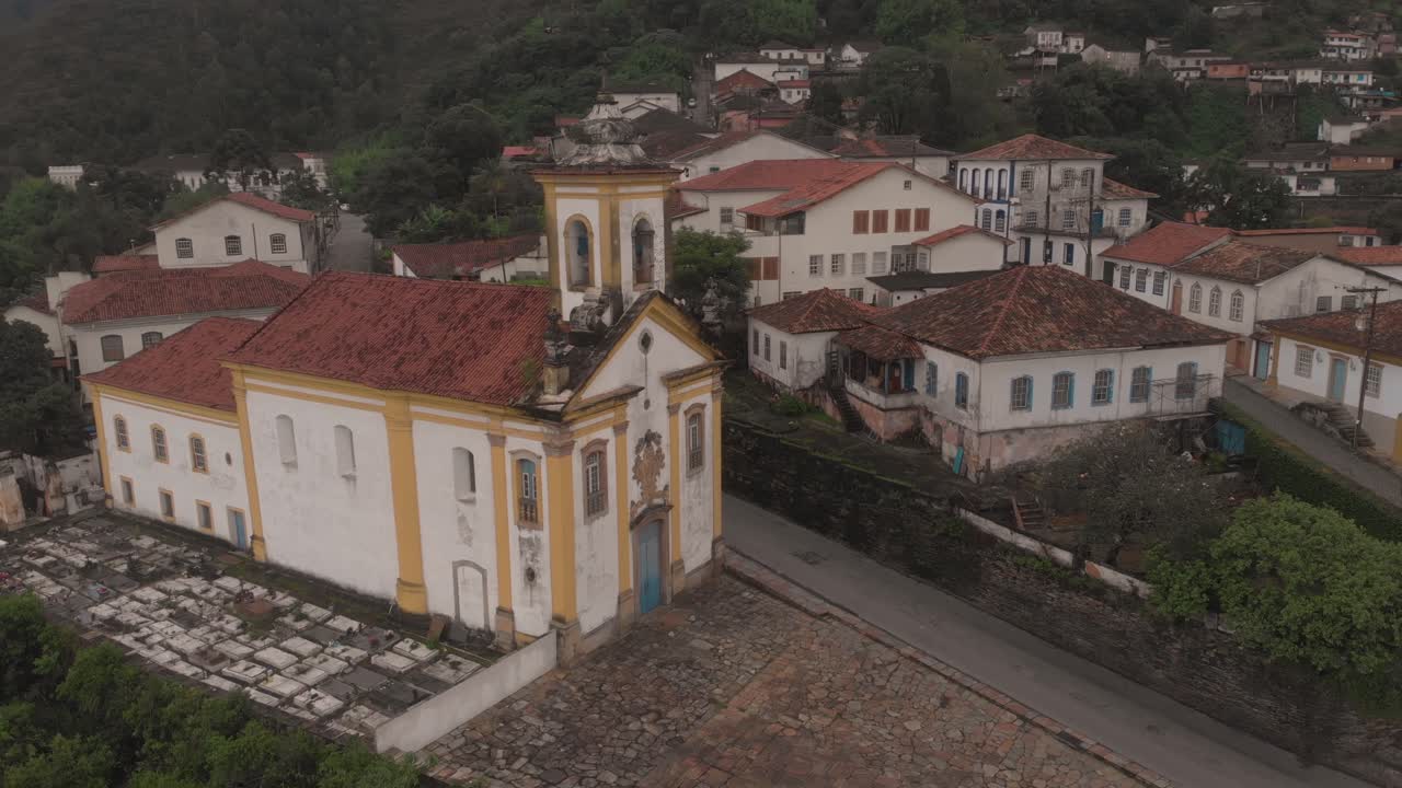 Aerial rotating pan showing the exterior facade of the Our Lady of Mercy and Charity church in Ouro Preto, Minas Gerais, Brazil, with a small cemetery beside
