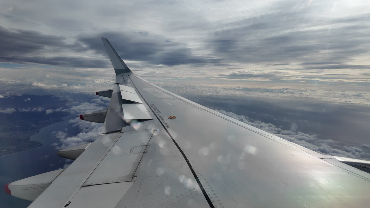 Aircraft wing gliding above layered clouds viewed from the window seat