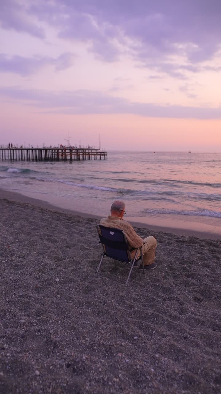 해가 지면 해변에서 휴식을 취하는 노인