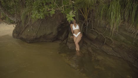 Ein-Model,-Das-In-Einem-Mikro-Bikini-In-Einem-Fluss-Sitzt-Und-Für-Den-Videodreh-Posiert