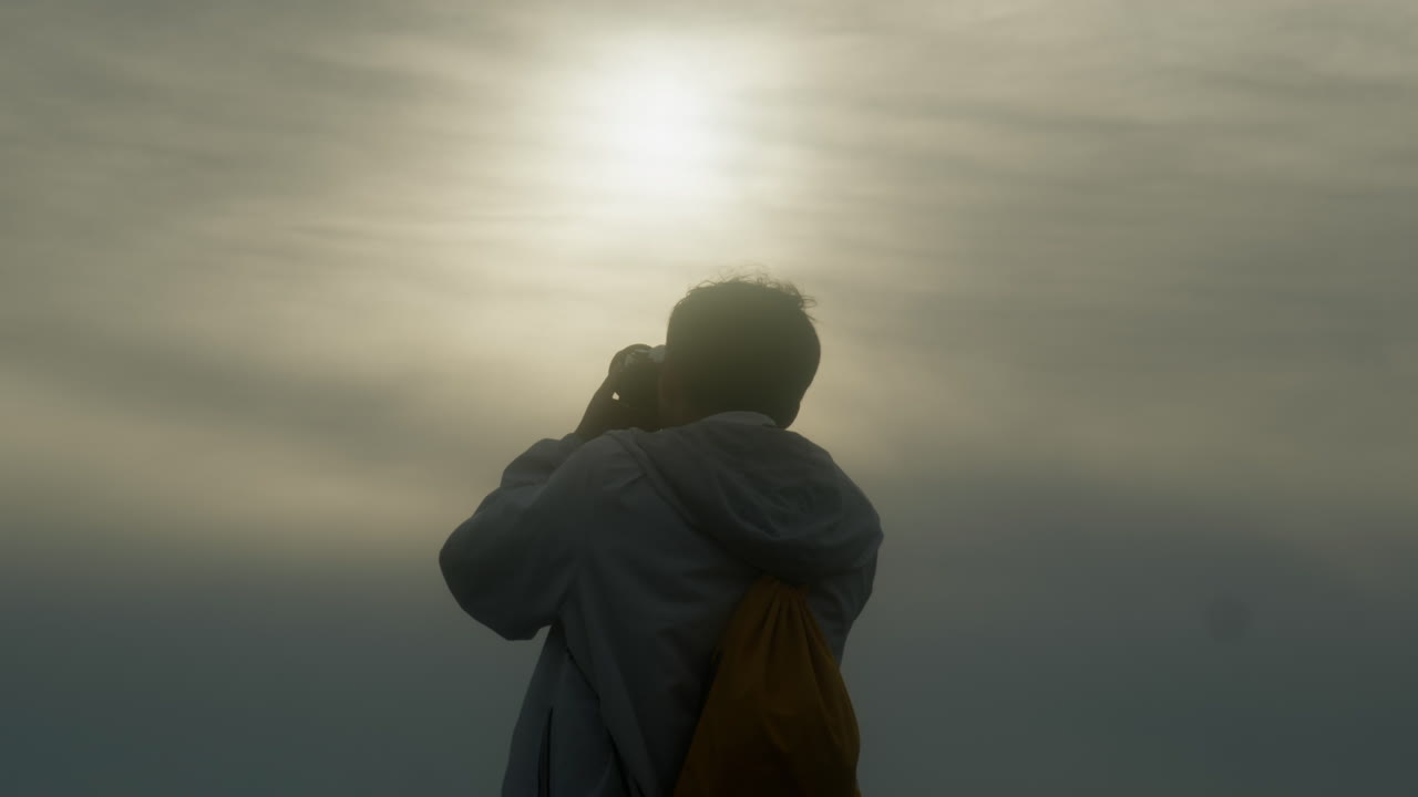 cámara lenta de fotógrafo profesional creador de contenido disparando contra el sol con niebla y cielo nebuloso