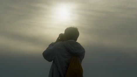 Zeitlupe-Eines-Professionellen-Fotografen,-Der-Content-Ersteller-Ist-Und-Gegen-Die-Sonne-Mit-Dunst-Und-Nebligem-Himmel-Fotografiert