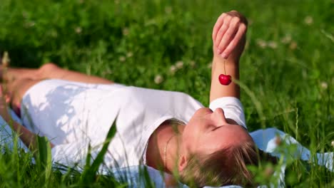 beautiful girl tastes ripe red cherries young woman on the lawn and enjoys the cherries