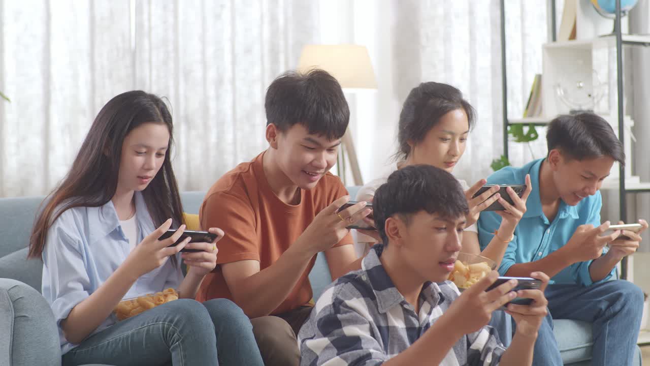 เพื่อนวัยรุ่นเอเชียกำลังเล่นวิดีโอเกมบนสมาร์ทโฟนที่บ้านและรู้สึกผิดหวัง