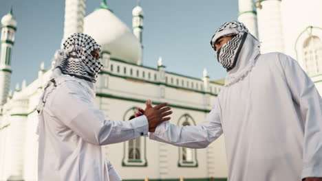 two men in traditional arabic clothing in front of a mosque