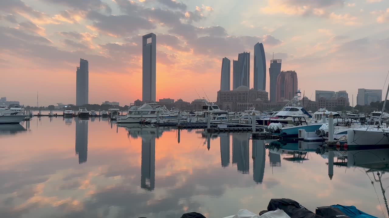 Gyllen soloppgang over Emirates Palace Marina, Abu Dhabi, De forente arabiske emirater med byens skyline, luksusyachter og fargerik soloppgang som reflekteres i vannet