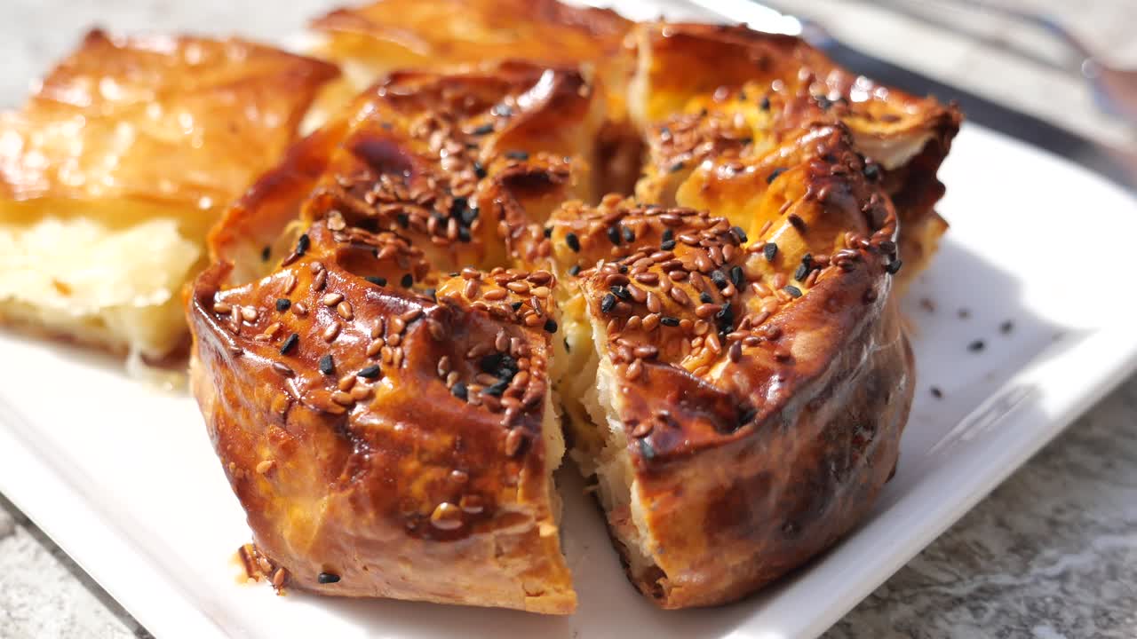 Close-up of a golden-brown savory pastry topped with sesame and black seeds