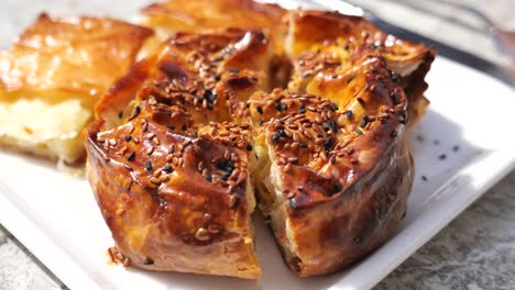 close-up of a golden-brown savory pastry topped with sesame and black seeds