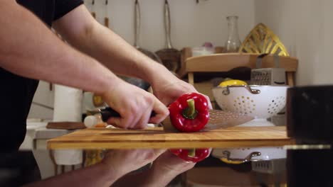 chef cuts big red pepper on the cutting board, in the kitchen