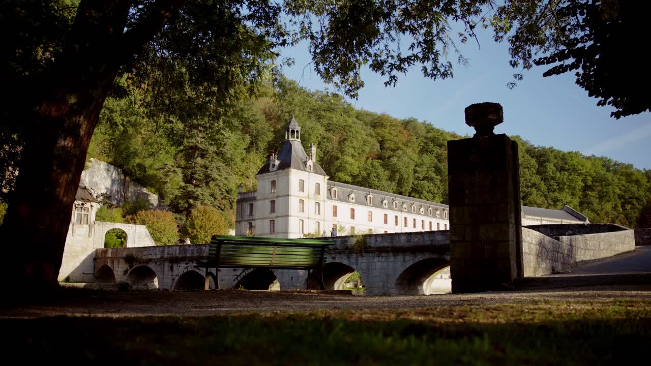 Abbazia pittoresca in Francia: ponte in pietra, panchina verde e paesaggio suggestivo