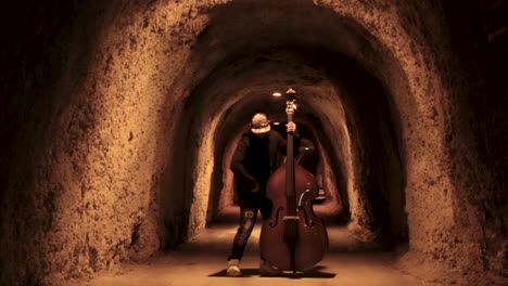 double bass player in a cave tunnel