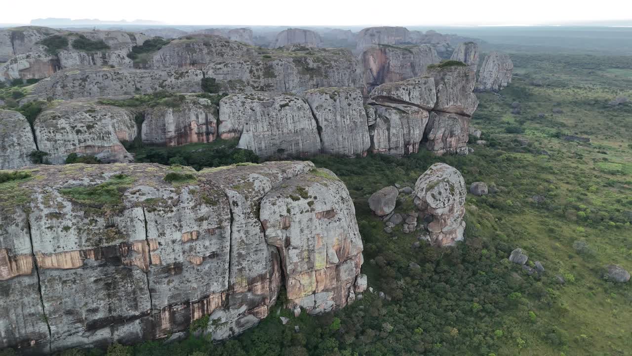 Volo cinematografico durante le ore dorate sopra gli antichi giganti di pietra di Pungo Andongo, Malanje, Angola, Africa, che evidenzia il contrasto tra i monoliti scuri e le pianure verdi