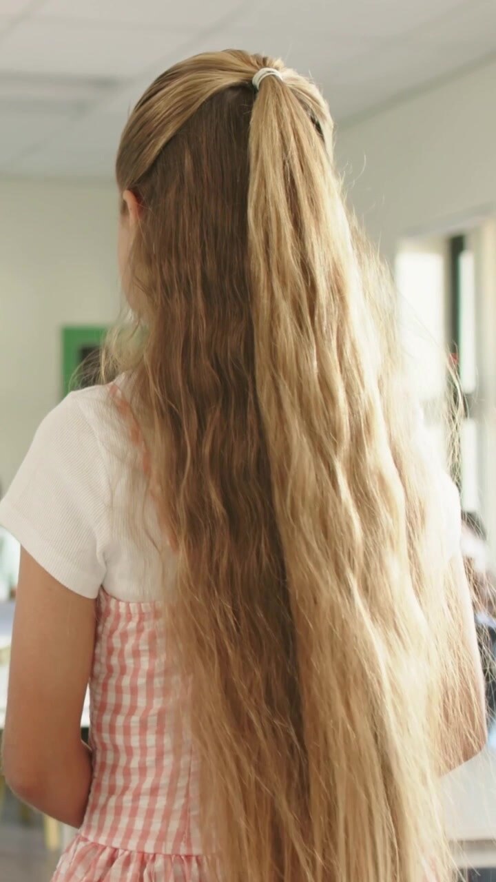 Studentessa adolescente in piedi davanti ai compagni di scuola che la osservano, causando movimenti, girando la testa e facendo ondeggiare i capelli.