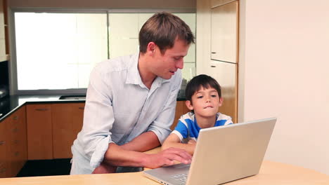 father and son with laptop in the kitchen