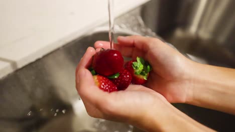 manos lavando fresas en un fregadero de la cocina