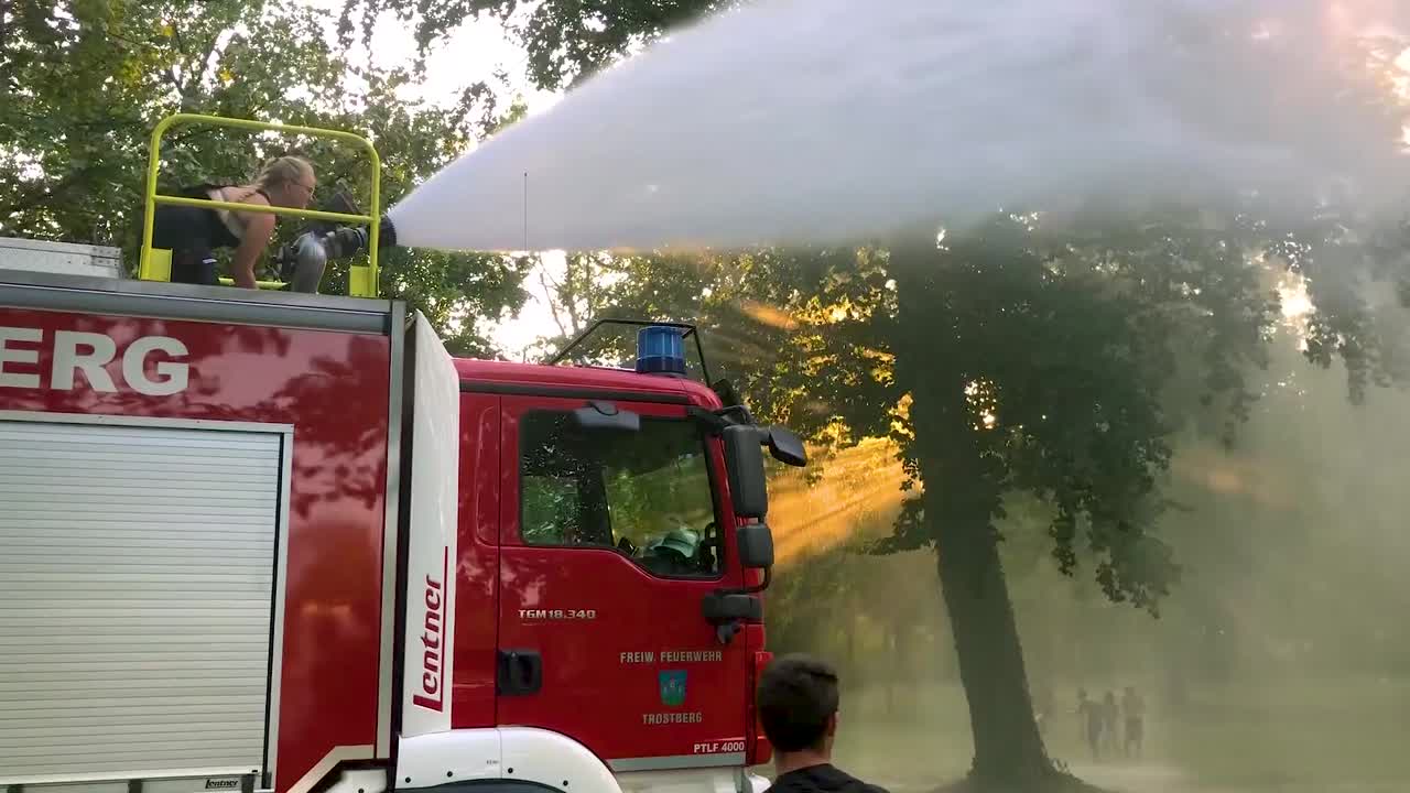 camión de bomberos alemán rociando agua para niños y árboles en un caluroso día de verano-1