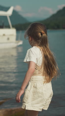 active girl runs to yacht moored by seashore on warm day in summer. entertainment and water transport with scenic sea view in sunny weather