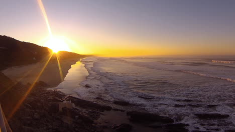 timelapse: impresionante amanecer dorado sobre un largo tramo de playa, olas rodando