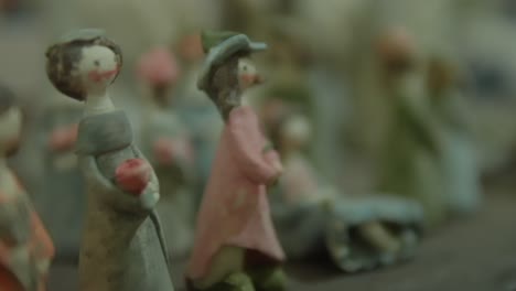 close-up of small painted clay figurines depicting women in vintage attire, arranged together on display