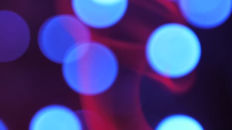 el humo rojo sube lentamente, las luces redondas se mueven en el fondo, el humo y las luces se desdibujan
