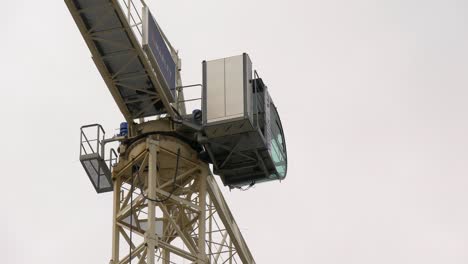 Static-high-view-of-top-operators-booth-of-construction-tower-crane-against-grey-white-sky