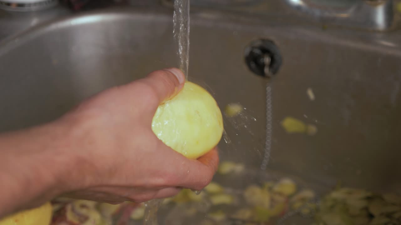 Lavando patatas peladas bajo el grifo abierto