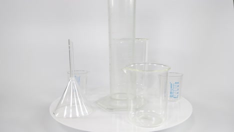 various clear beakers rotating on a platform