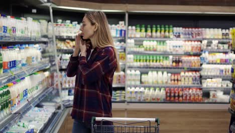 woman shopping in supermarket while talking using mobile