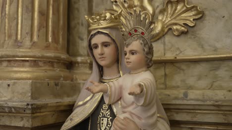 estatua de la virgen maría con el bebé jesús, ambos con coronas, exhibida en una iglesia con acentos de oro