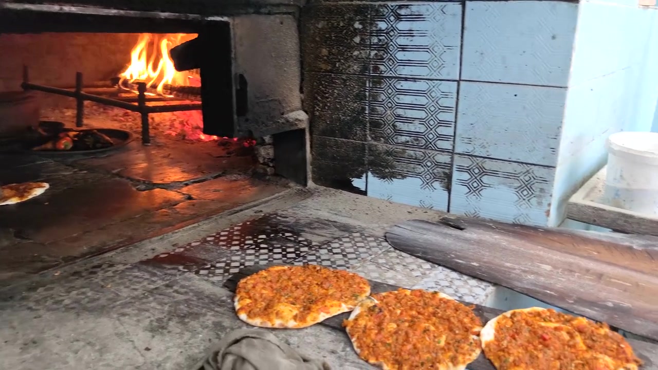 Leipuri valmistaa ja paistaa perinteistä lahmacunia puu-uunissa