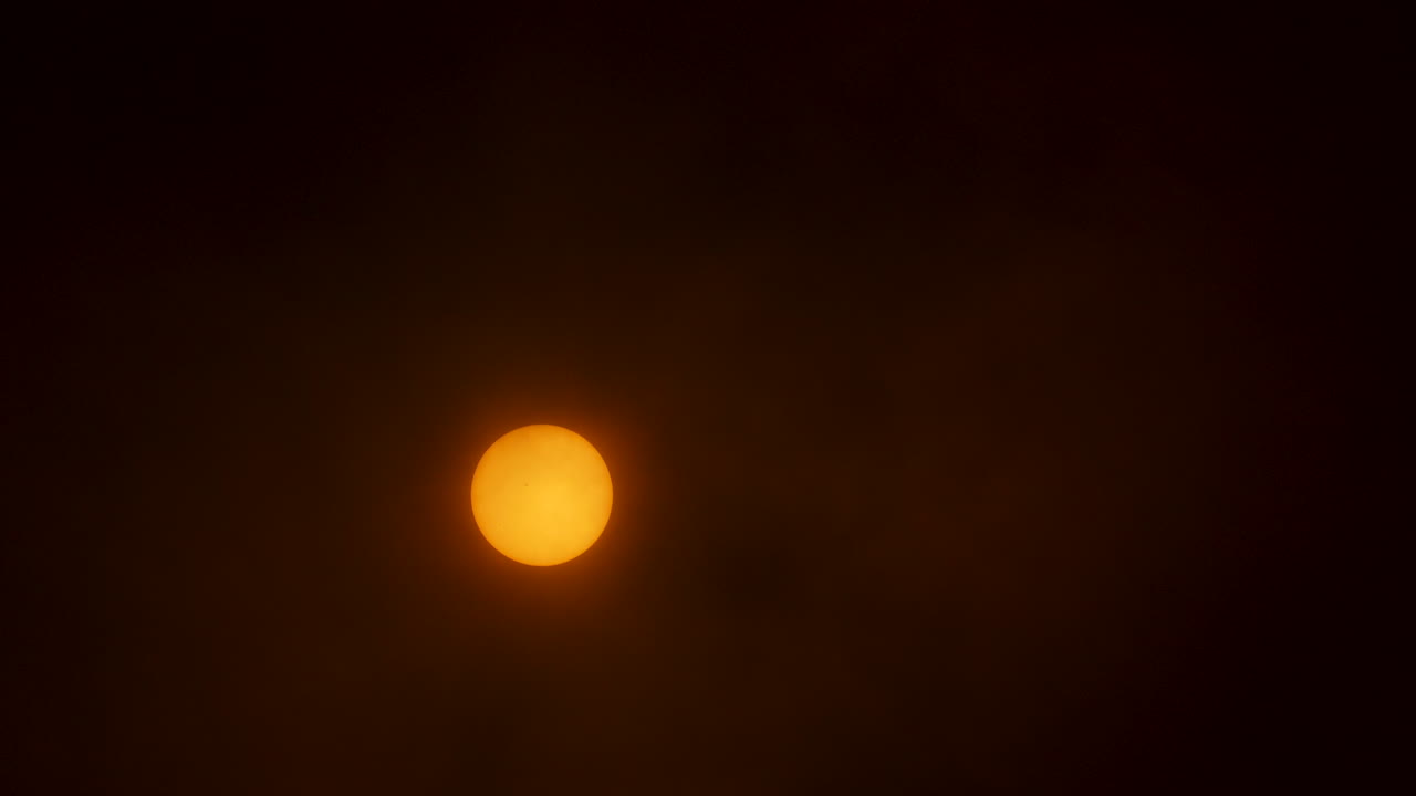 The sun with thin hazy clouds moving in front of it