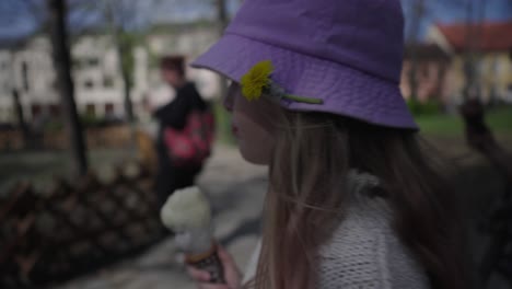 Una-Chica-Con-Un-Diente-De-León-En-Un-Sombrero-Rosa-Caminando-Por-El-Parque-Lamiendo-Un-Cono-De-Helado