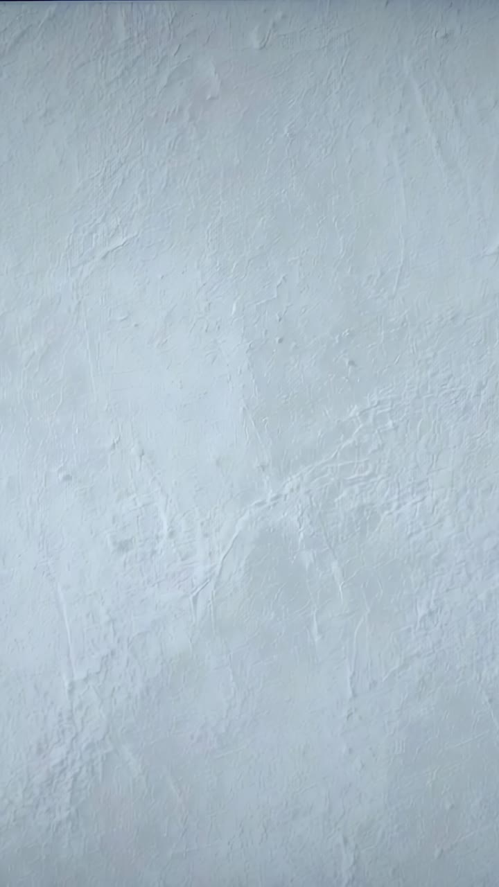 Vertical video: Shifting light creating faint band on painted plaster wall at home, exposure change