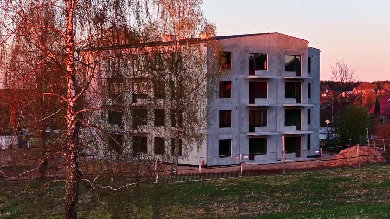 Nuovo condominio moderno con facciata in cemento in costruzione durante un tramonto dorato.