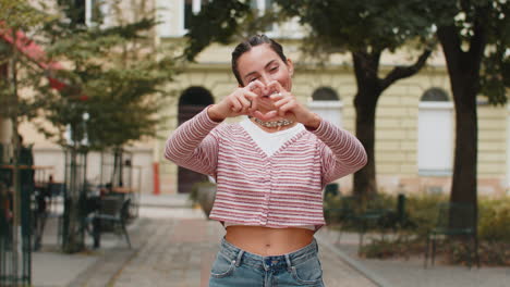 caucasian woman makes symbol of love showing heart sign to camera express romantic feelings charity