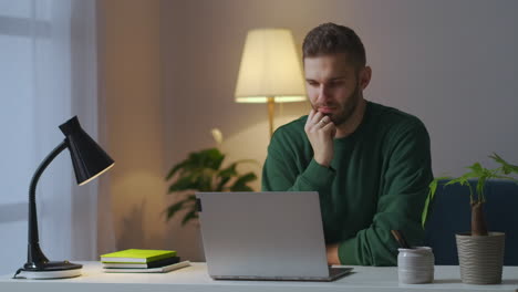 Ein-Erwachsener-Mann-Sieht-Sich-Zu-Hause-Abends-Auf-Dem-Notebook-Ein-Video-Oder-Kino-An,-Lernt-Und-Unterhält-Sich-Am-Tisch