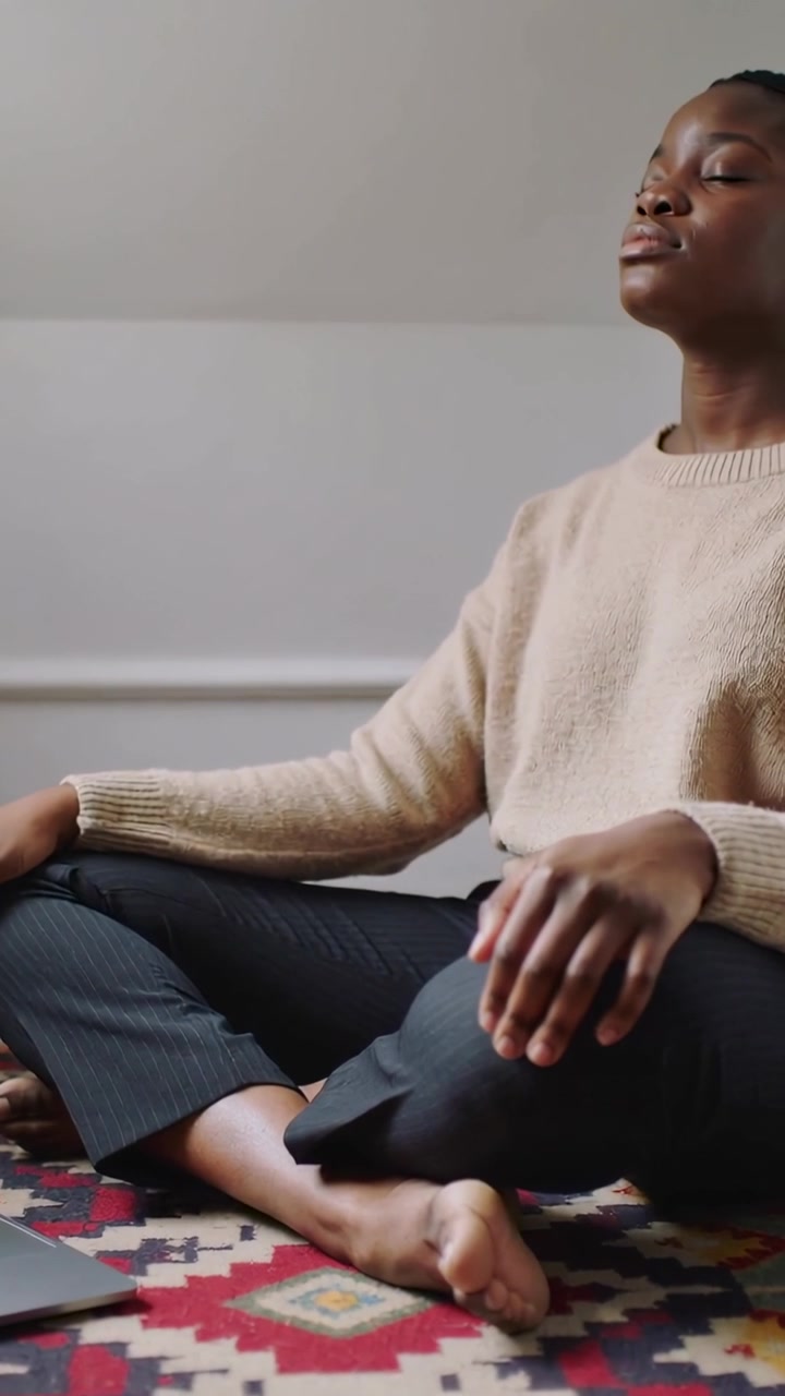 Vertikal video: Meditation börjar, kvinna i beige tröja andas hemma på matta med laptop